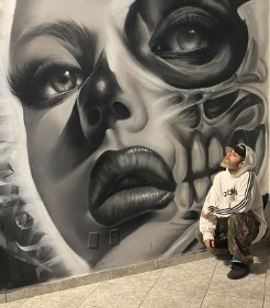 Grafite de rosto feminino em muro, com o artista
